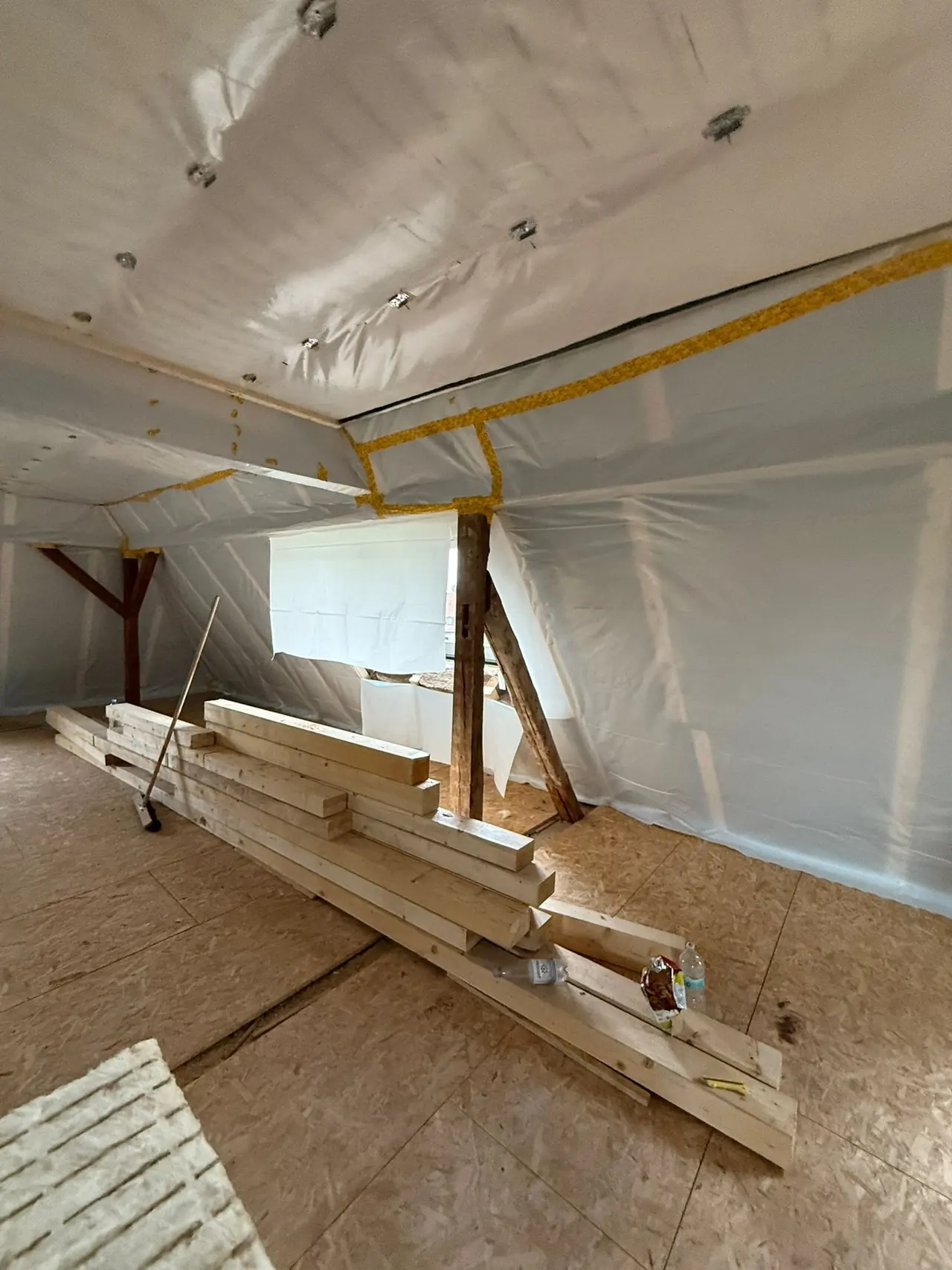 Augsburg, Küchenzone vor dem Ausbau: rohe Dachfläche mit gestapelten Holzlatten, noch ohne Einbauten