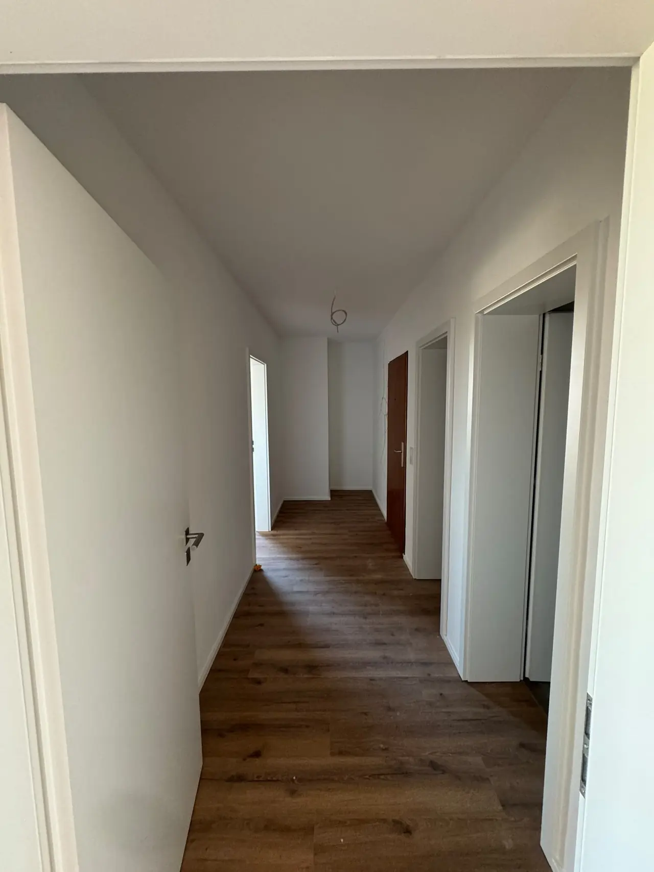 Straubing, Flur nach der Sanierung: weiße Wände, neue Türen und durchgehender Boden in Holzoptik